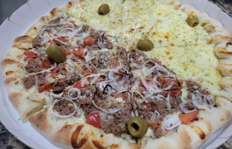 Foto de uma pizza meia mussarela e meia carne com cebola.